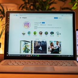 A computer on the table showing an Instagram profile