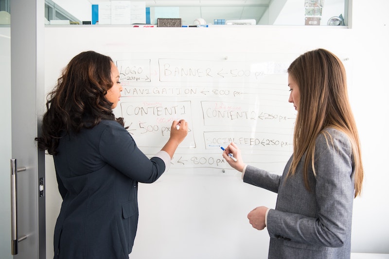 two content developers standing in front of the board